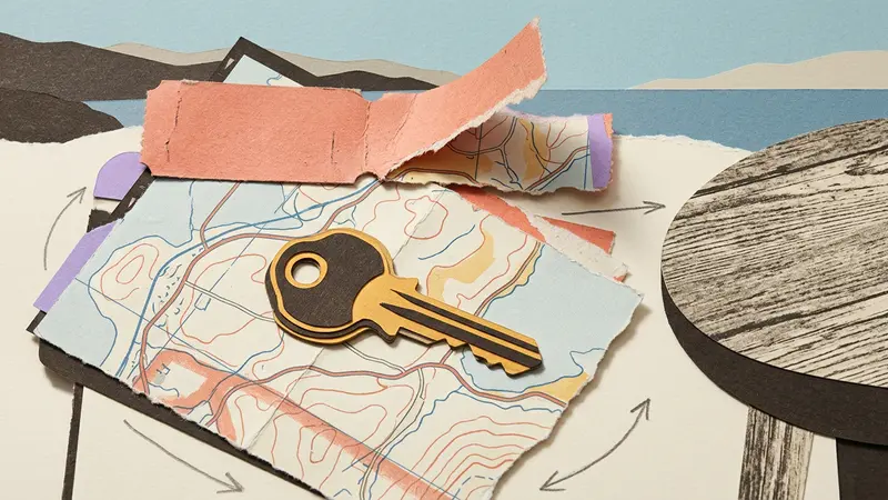 Papercraft of a brass key on a folded map with a torn ticket strip on a table.