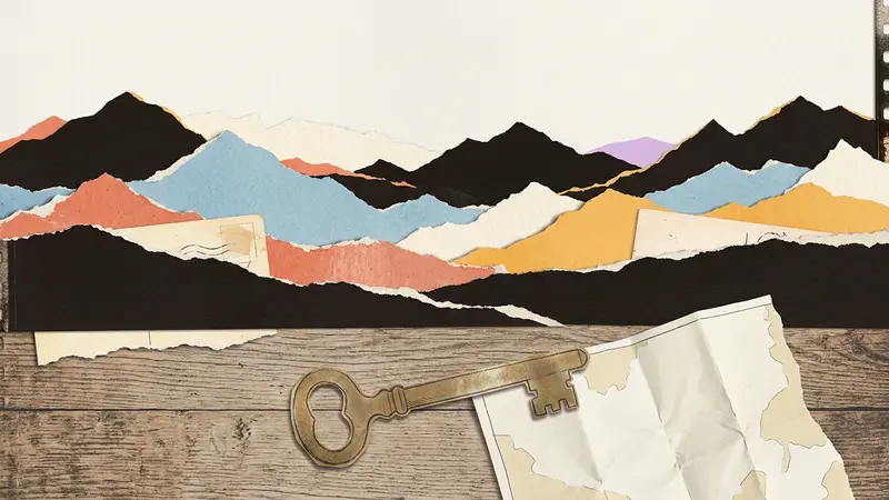 A brass room key resting on a wooden table in front of layered paper mountain silhouettes.