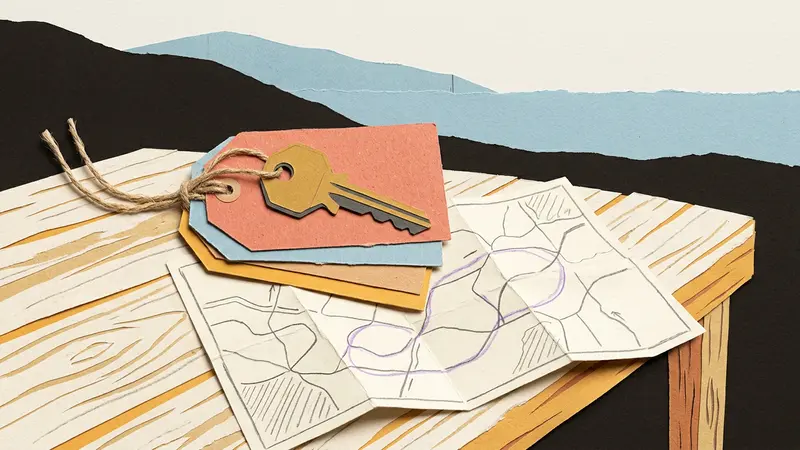 A close-up of blank luggage tags and a brass key atop a folded paper map on a wooden table.